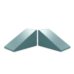 Two teal-colored Mega Wedge Play Triangles from Foamnasium placed side by side with their sloped sides facing inward. Made from durable foam and GREENGUARD GOLD Certified, they have a smooth surface and are used for various fitness, therapeutic, or supportive purposes.