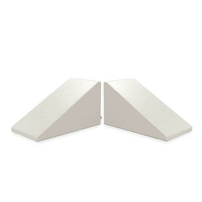 Two Mega Wedge Play Triangles by Foamnasium, GREENGUARD GOLD Certified, are arranged with their angled sides facing each other, creating a symmetrical appearance. These white triangular foam wedges are likely used for support or positioning. The background is plain white.